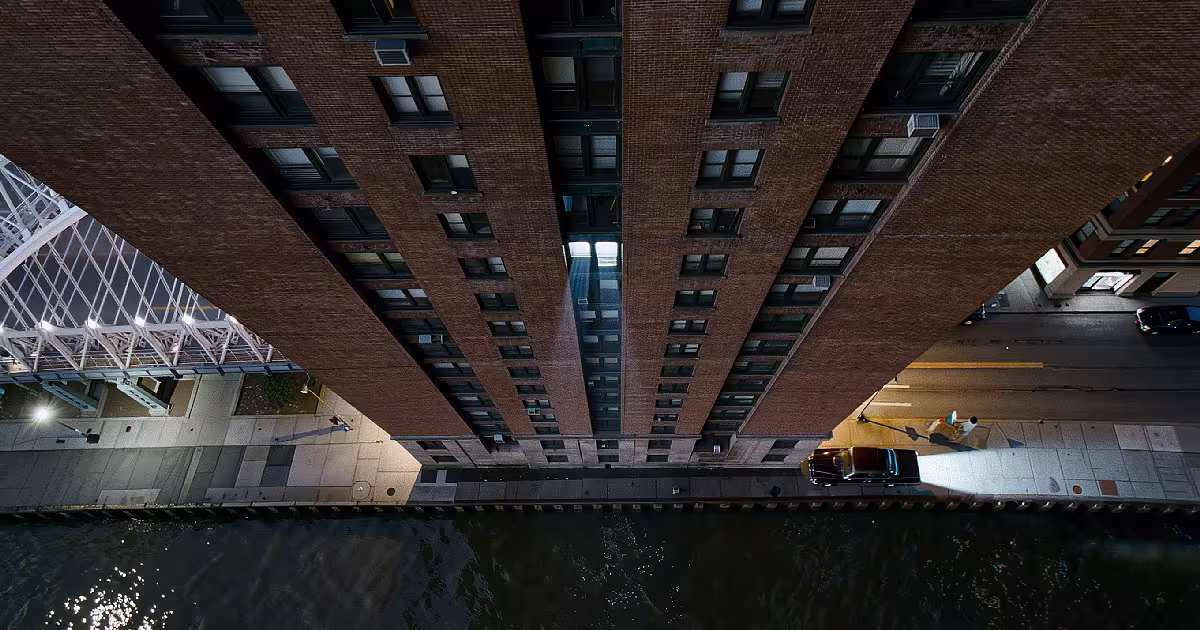 Manhattan apartment block at 3 a.m. Bridge lights, one window lit. Illustration.